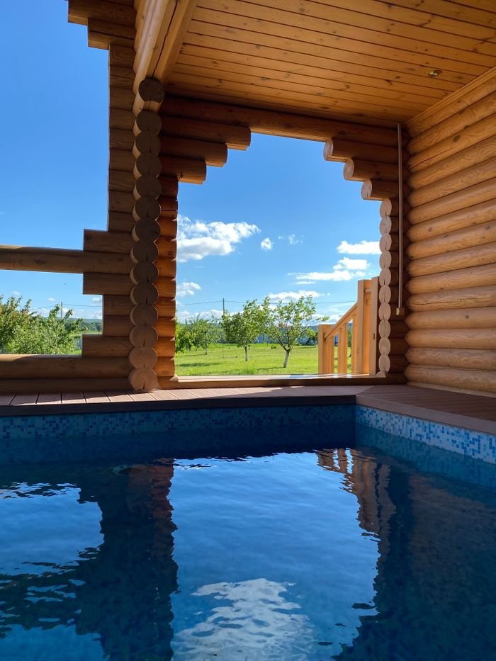 A beautiful wooden cabin with a pool, overlooking a scenic countryside view.
